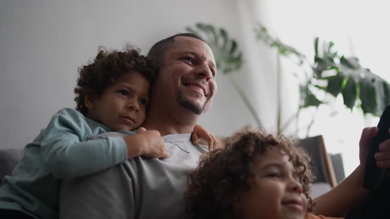 Father and sons watching TV at home