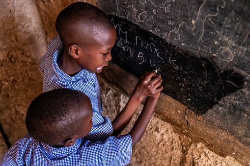 African children during their English class in orphanage - they helping each other to write. There is no light and electricity inside the classroom. Around 20-30 orphans live in this orphanage which is located near Nairobi.