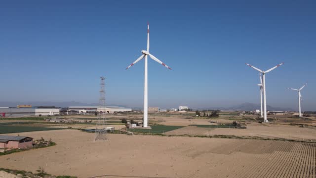 The coastline under the blue sky and the wind turbines on the beach