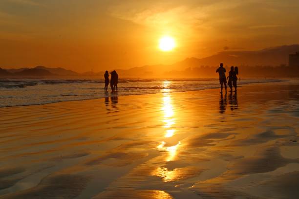 istock Golden bright sunset with people silhouette over the beach sand 1398198154