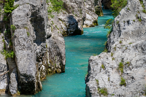 Turquoise water flowing between dolomite rocks on sunny day. Beautiful nature scene. Soca river, Slovenia.