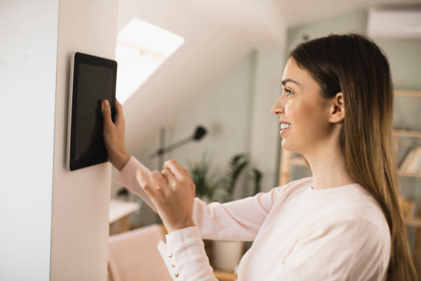 istock Happy young woman adjusting a smart system at her house 1398204251