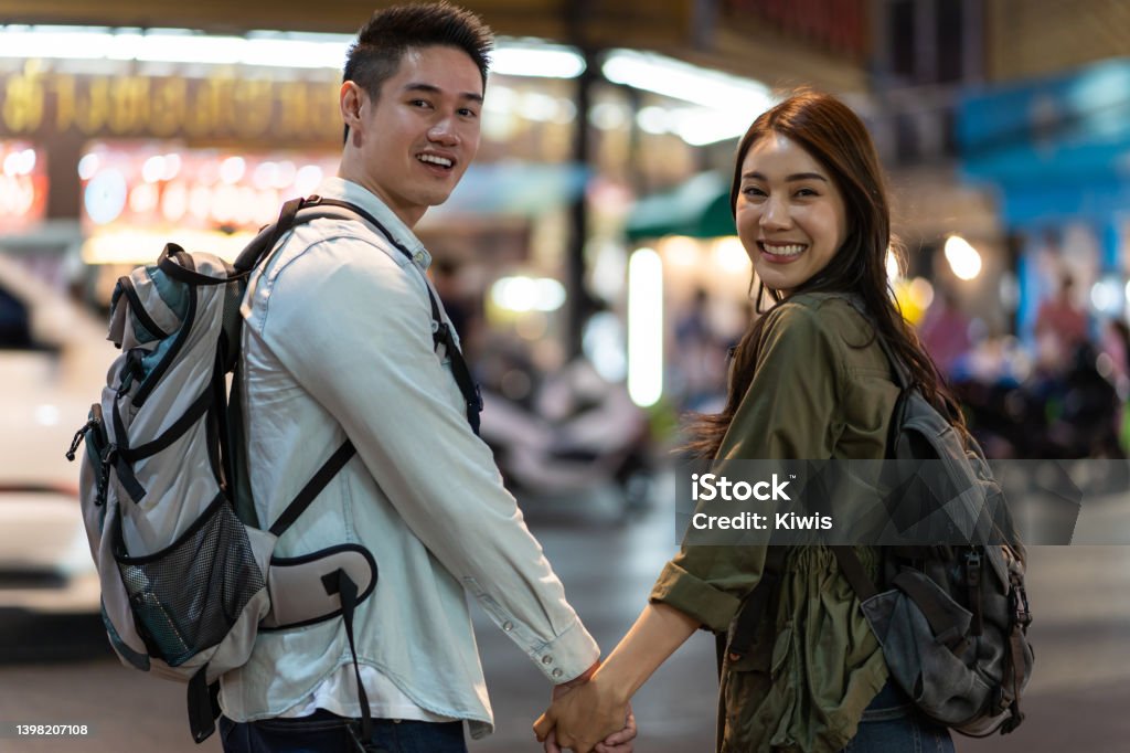 Portrait of Asian couple travel in city for honeymoon trip at night. Attractive young new marriage man and woman backpacker tourist enjoy spend time on holiday vacation together and looking at camera. Couple - Relationship Stock Photo Portrait of Asian couple travel in city for honeymoon trip at night. Attractive young new marriage man and woman backpacker tourist enjoy spend time on holiday vacation together and looking at camera. Couple - Relationship Stock Photo