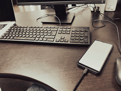 Office desk with desktop PC; laptop and smartphone