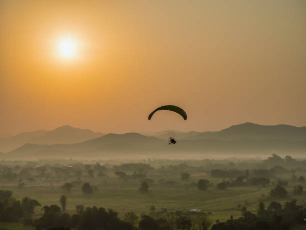 istock Sillhouette paramotor on the sky with a beautiful scenery in the the morning. 1398217515
