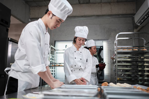 istock Chefs team in uniforms prepare to bake bread and pastry in stainless kitchen. 1398220854