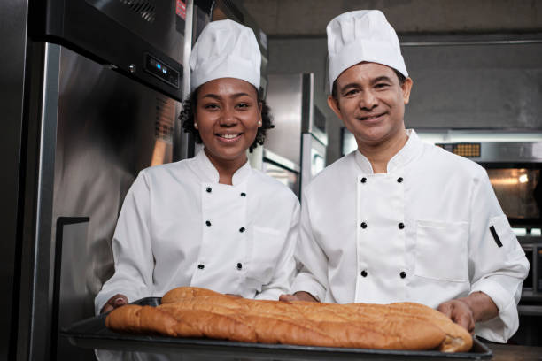 Two professional chefs with baking bread, smile and are cheerful in the kitchen. stock photo