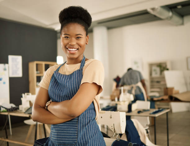 poderosa empresária com os braços cruzados. retrato do principal empresário. empreendedora afro-americana em sua oficina de design. jovem dona de um pequeno negócio em seu estúdio de design - working tailor stitch sewing - fotografias e filmes do acervo