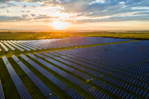 vista aérea de una gran planta de energía eléctrica sostenible con muchas filas de paneles solares fotovoltaicos para producir energía eléctrica limpia al atardecer. electricidad renovable con concepto cero emisiones. - música industrial fotografías e imágenes de stock