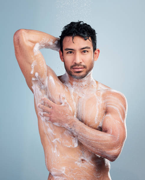 portrait d’homme faisant mousser son corps. jeune homme appliquant du savon sur son corps sous la douche. homme hispanique nettoyant son corps. homme frottant de la mousse de savon sur son corps. soins du corps mutliracial pour homme, routine de soins de - shower portrait male beauty chest photos et images de collection