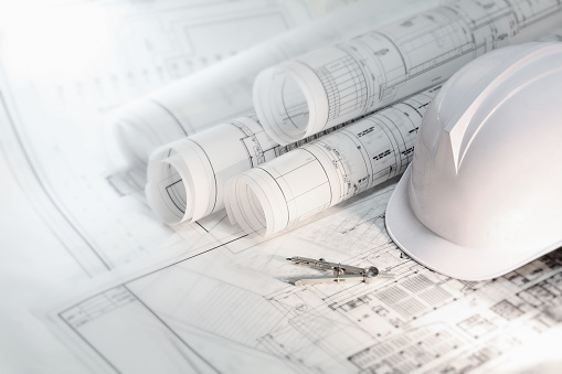 Hard hat and compass on architectural blueprints and construction technology and future industry