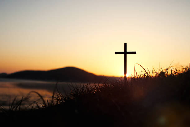 święty krzyż jezusa chrystusa na trawie z silnym światłem na niebie o zachodzie słońca - cross shape obrazy zdjęcia i obrazy z banku zdjęć