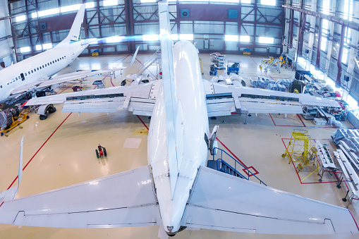 Top view of a white passenger aircrafts in the hangar. Airplanes under maintenance. Checking mechanical systems for flight operations