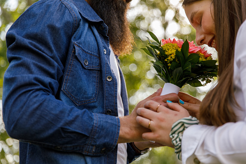 Cut out shot of joyful young woman smelling a beautiful bouquet of flowers that her caring boyfriend is giving to her.