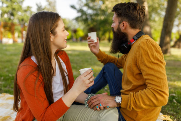 istock Couple holding hands and enjoying drinks during picnic at the park 1398230372