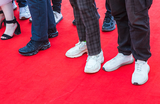 Feet of prom guests standing on a red carpet, close up photo