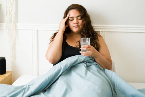 Stressed woman feeling sick because of a hangover Sad woman with obesity suffering from a headache and a hangover after a night of drinking hangover stock pictures, royalty-free photos & images