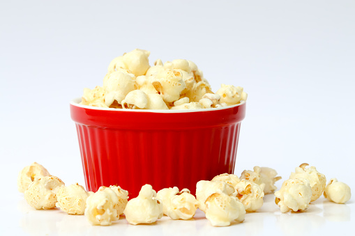 Caramel popcorn on red bowl and white background.