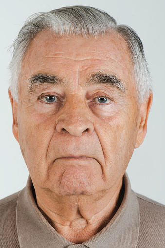 Portrait of a senior man isolated on a gray background.