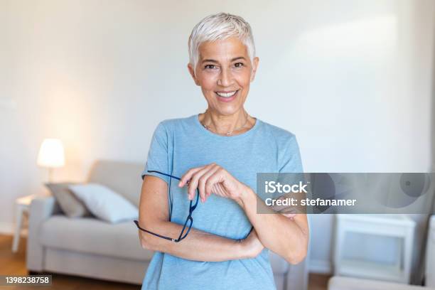 Portrait Of Beautiful Senior Woman Holding Glasses Looking In Camera Stock Photo - Download Image Now