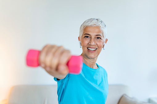 Senior woman exercise with dumbbells at home . happy mature woman doing arm workout using dumbbells. Elderly woman prefers healthy lifestyle