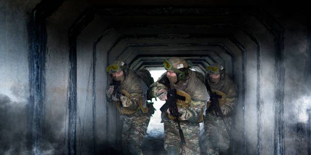 Photo format 2x1.Three military mercenaries during special operation against the background of a concrete tunnel and smoke.