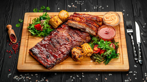 Spicy hot grilled spare ribs from a summer BBQ BBQ ribs with sweet and sour sauce, served with roasted corn plate rack stock pictures, royalty-free photos & images
