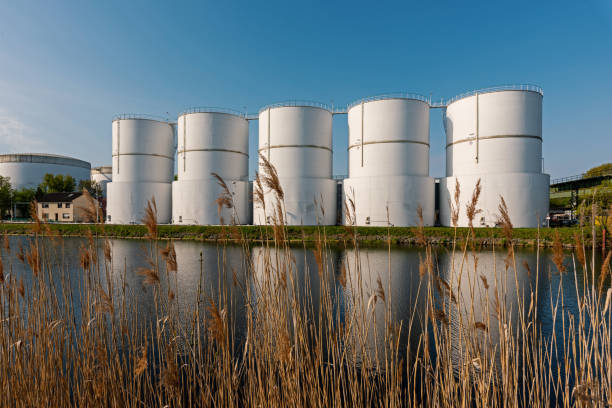 Oil supply. large white steel reservoirs of a tank farm for mineral oil at a canal. stock photo
