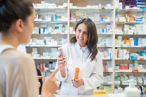Female Pharmacist Consulting With Patient In Pharmacy