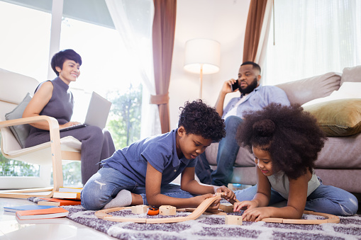 Happy African American family. little boy and girl having fun and play toys in the living room