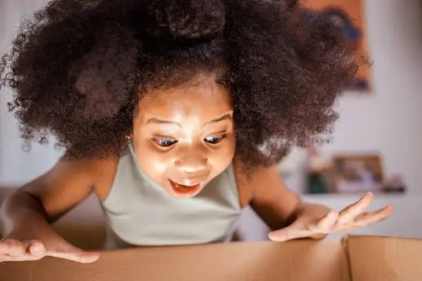 Photo of New house happy homeowners family. Surprised girl unpack big gift box at home