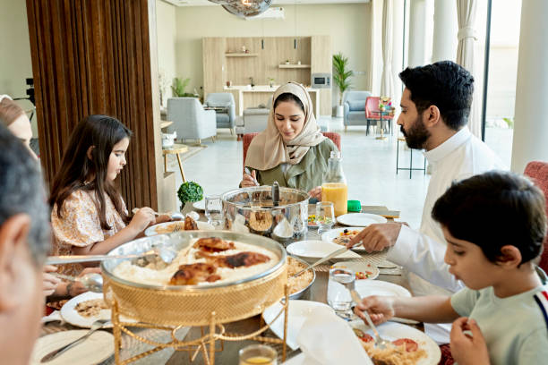 jovens familiares e parentes sauditas desfrutando da refeição do meio-dia - saudi arabia child ramadan offspring - fotografias e filmes do acervo