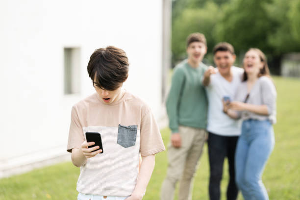 Teenager boy suffering cyber bullying Teenager boy looking at phone and suffering cyber bullying. online bullying stock pictures, royalty-free photos & images