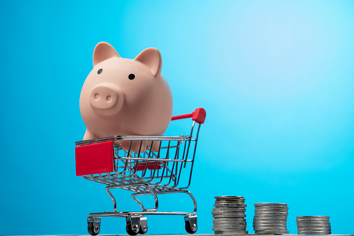 Shopping cart with coins money and white piggy bank. investment business sale and purchase. save and pay concept