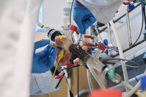 Unrecognizable researchers taking sample from a reactor in a laboratory.