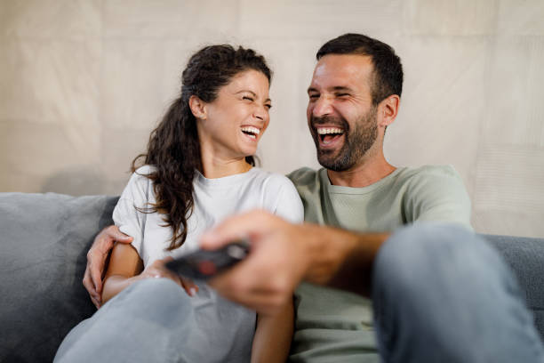 istock Cheerful couple enjoying while watching TV at home. 1398254436
