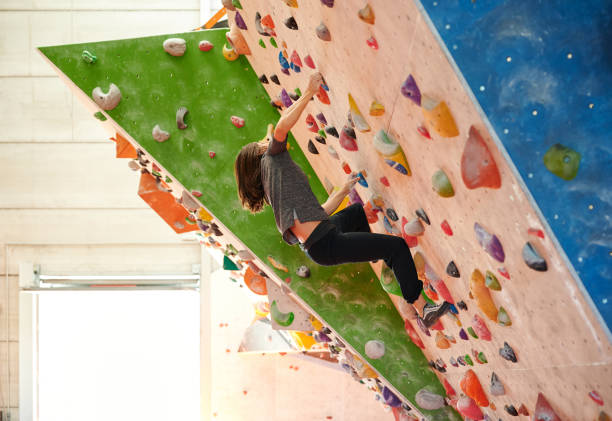 istock Brunette tilting back and climbing angled wall during boulder training in daytime in light gym 1398258325
