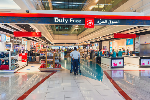 Dubai, UAE - April 27 2020: Passengers passing through Dubai Duty Free stores which is home to nearly all brands. Dubai International Airport Terminal, one of the busiest airports in the world. The airport terminal has all the required modern amenities such as restaurants, retail space, gaming arcades, prayer rooms, relaxation facilities such as spa and hotels.