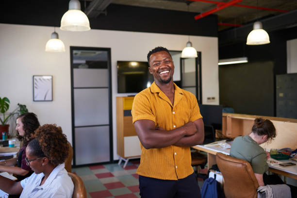 istock A Black business owner stands with his arms crossed while creative team works 1398260553