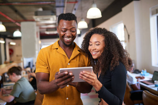 istock Two creative colleagues look at a digital tablet in an open plan office 1398260571