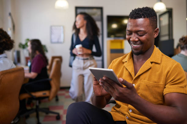 istock A Black businessman scrolls on his tablet in a busy diverse office 1398260572