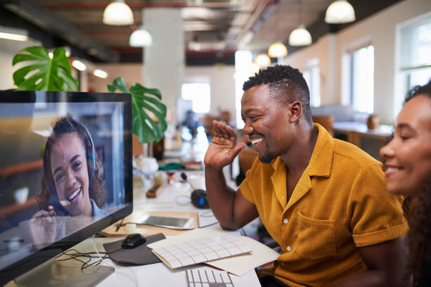 흑인 남성이 사무실에서 화상 통화로 동료에게 손을 흔들고 있습니다. - telecommuting 뉴스 사진 이미지