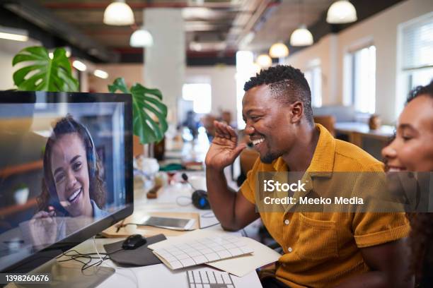 A Black Man Waves To His Colleague On A Video Call From His Office Stock Photo - Download Image Now