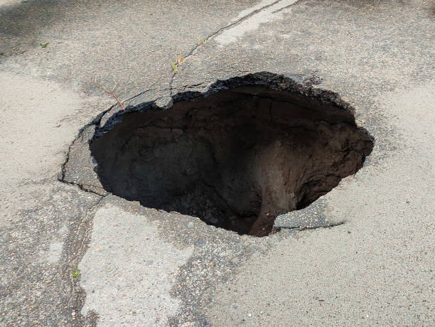 большая дыра в асфальте, воронка - pot hole стоковые фото и изображения