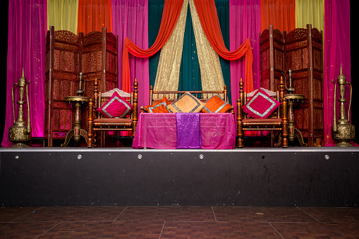 Decorated wedding stage for wedding couple. A wedding reception is a party usually held after the completion of a marriage ceremony as hospitality for those who have attended the wedding, hence the name reception. The couple receive society, in the form of family and friends, for the first time as a married couple.