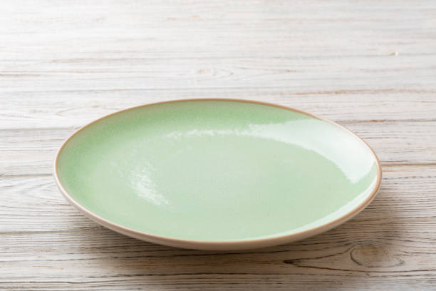 istock Perspective view of empty green plate on wooden background. Empty space for your design 1398262019