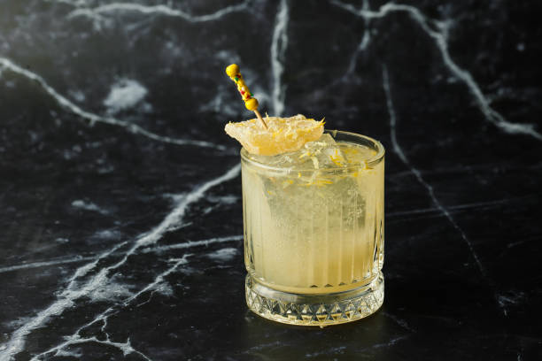 cóctel de bebida de penicilina alcohólica de whisky escocés con limón, jarabe de miel y jengibre confitado. copa de cóctel sobre fondo negro - penicillin fotografías e imágenes de stock