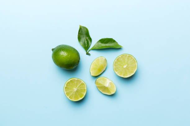 Lime fruits with green leaf and cut in half slice isolated on white background. Top view. Flat lay with copy space