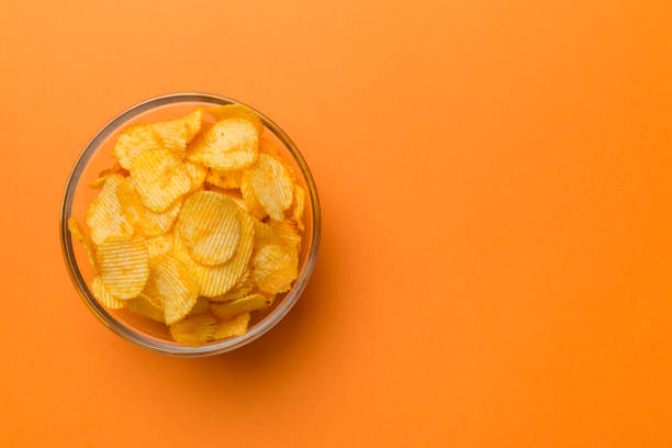 istock Potato chips on bowl isolated on colored background. Delicious crispy potato chips in bowl. Space for text. Top view 1398262102