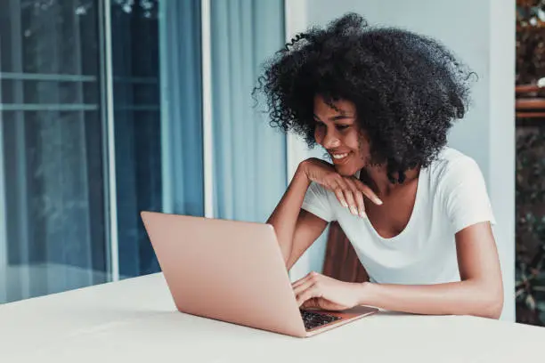 Photo of Young woman working on laptop at home in balcony.